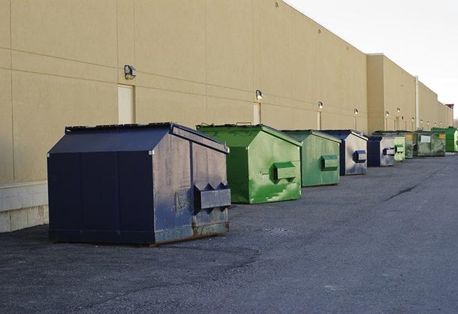 construction workers throw waste into a dumpster behind a building in Atherton